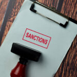 Close up Red Handle Rubber Stamper and text Sanctions isolated on White Background.
