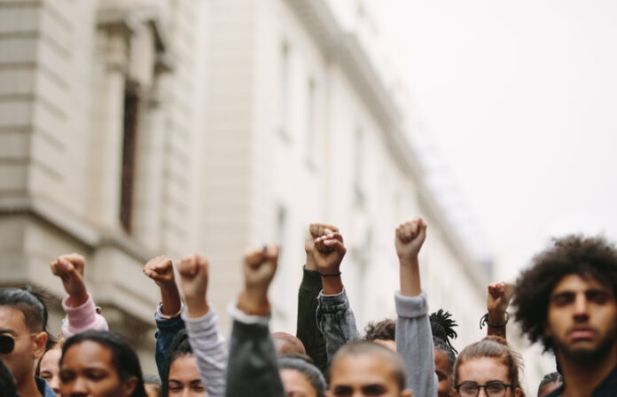 Arms raised in protest. Group of protestors fists raised up in the air.