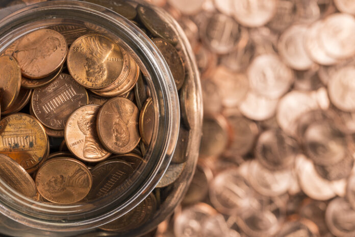 A jar of us pennies surrounded by pennies.