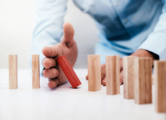 Businessman hand stop dominoes continuous toppled or risk with copyspace. Business risk, strategy and planing concept idea.